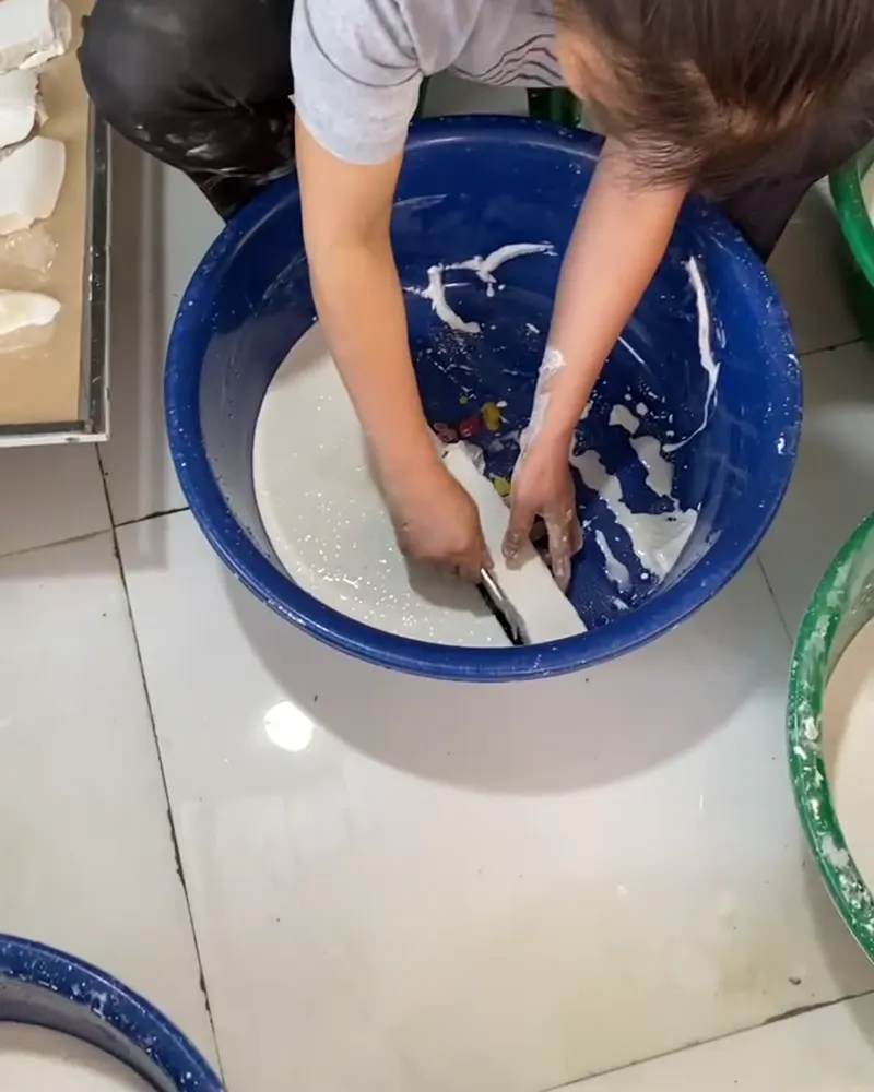 Lọc tay bột sắn dây trong chậu nước